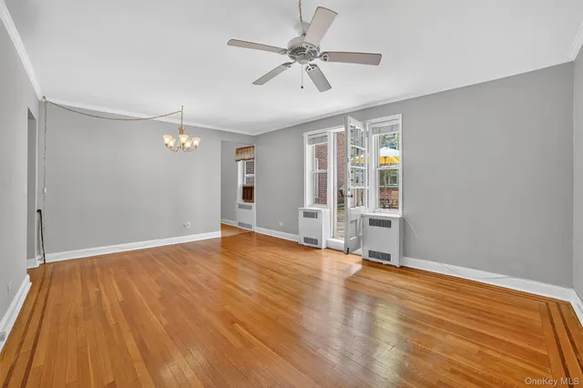 a view of an empty room with a window and wooden floor