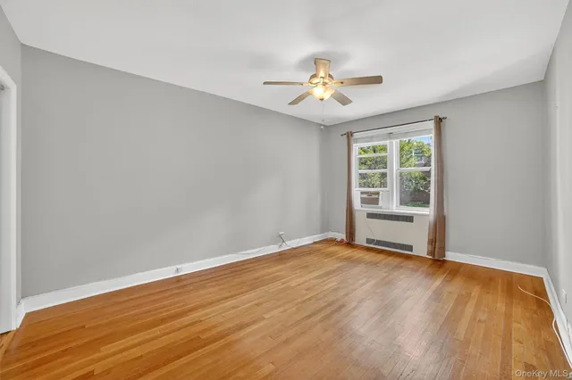 a view of an empty room with a window and wooden floor