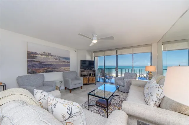 a living room with furniture kitchen view and a large window