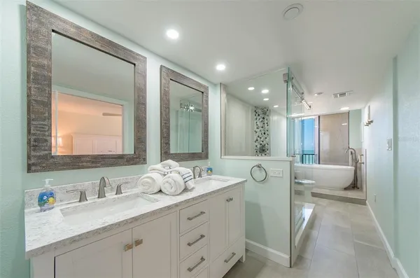 a spacious bathroom with a double vanity sink and mirror with shower