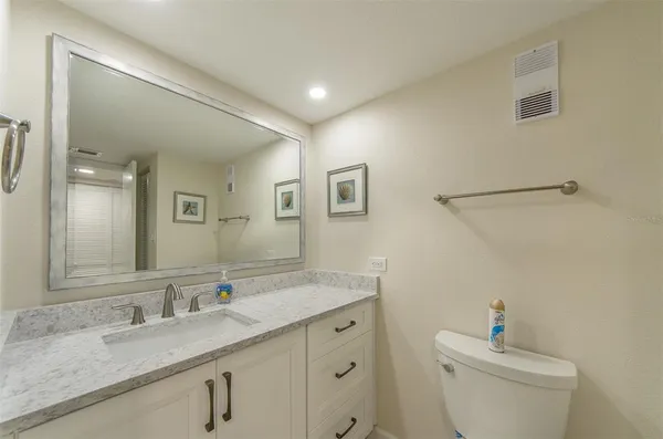 a bathroom with a granite countertop sink a large mirror a toilet and a shower
