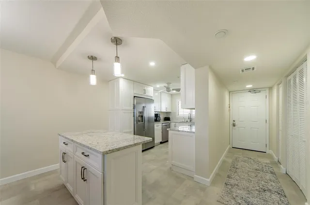 a bathroom with a granite countertop sink a refrigerator and cabinets