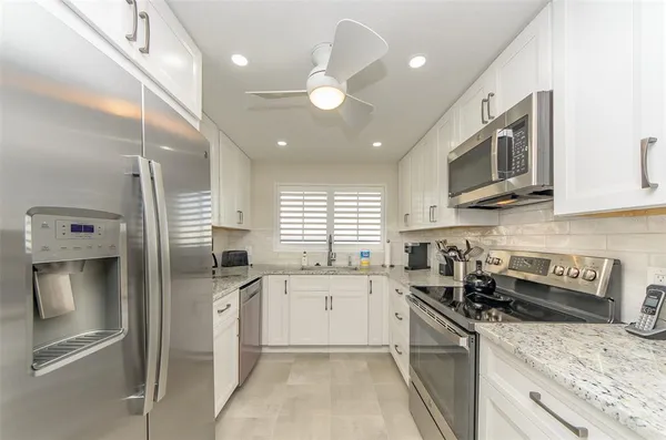 a kitchen with stainless steel appliances granite countertop a sink a stove and a refrigerator