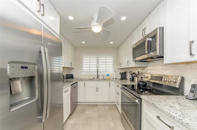 a kitchen with stainless steel appliances granite countertop a sink a stove and a refrigerator