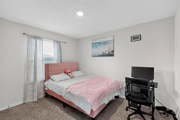 a bedroom with a bed and a laptop on a dresser