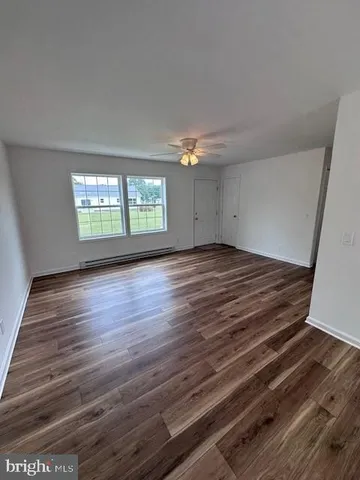 a view of an empty room with wooden floor and a window