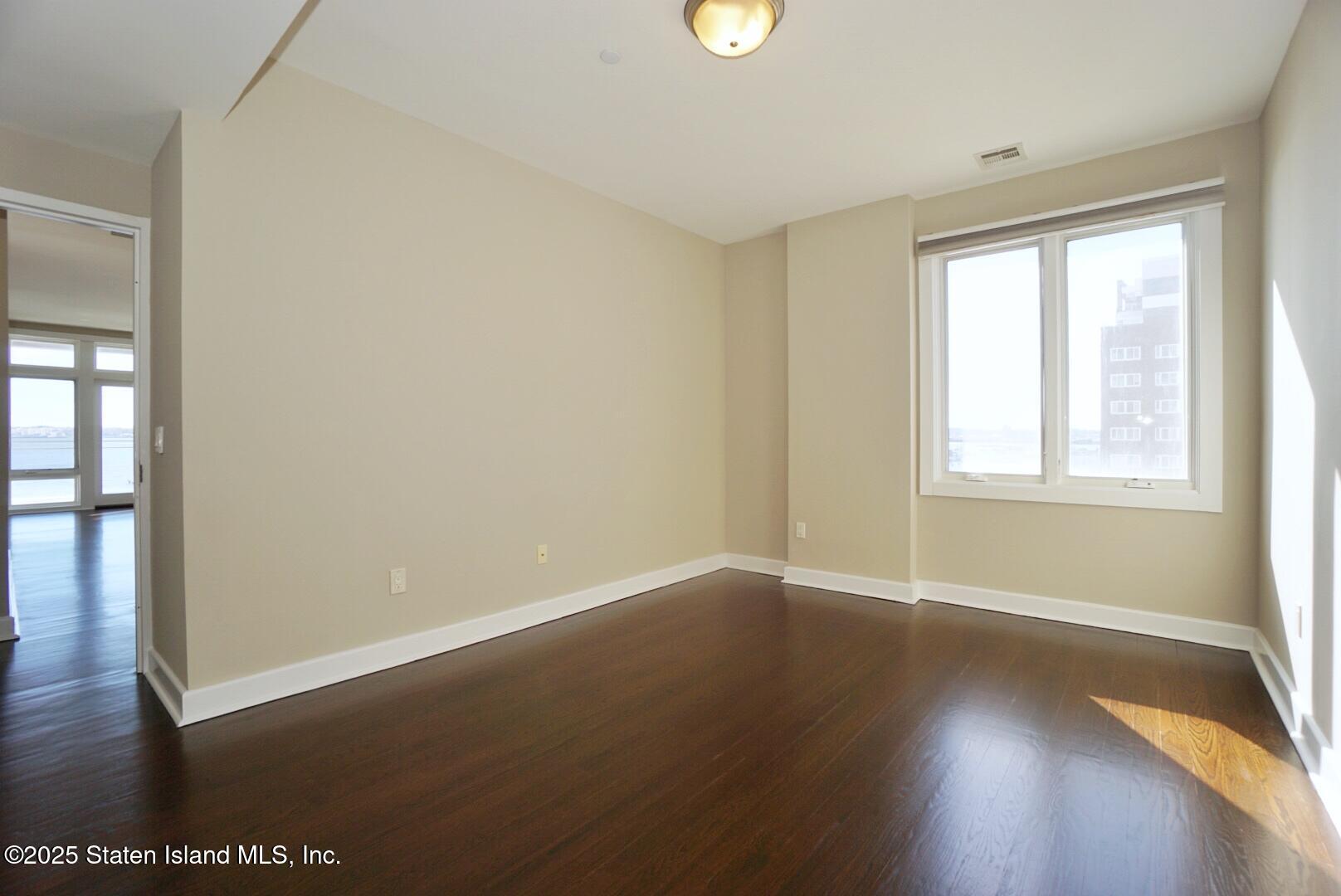 90 Bay Street Landing, Unit 4B Staten Island, NY 10301 - Photo 12 of 42 an empty room with wooden floor and windows