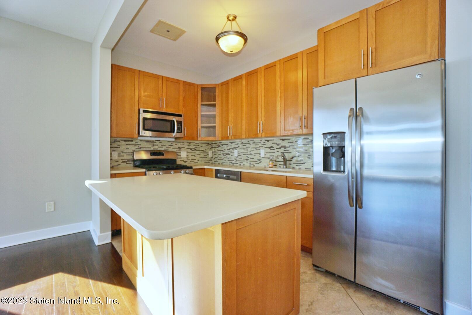 90 Bay Street Landing, Unit 4B Staten Island, NY 10301 - Photo 29 of 42 a kitchen with kitchen island a counter top space cabinets and a refrigerator