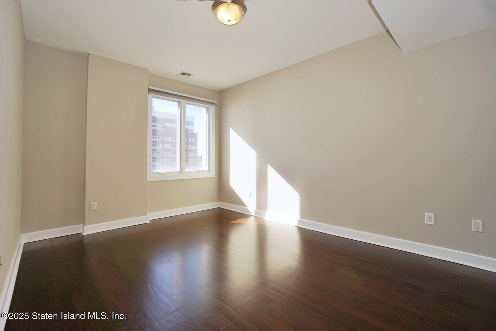 90 Bay Street Landing, Unit 4B Staten Island, NY 10301 - Photo 10 of 42 a view of an empty room with wooden floor and a window