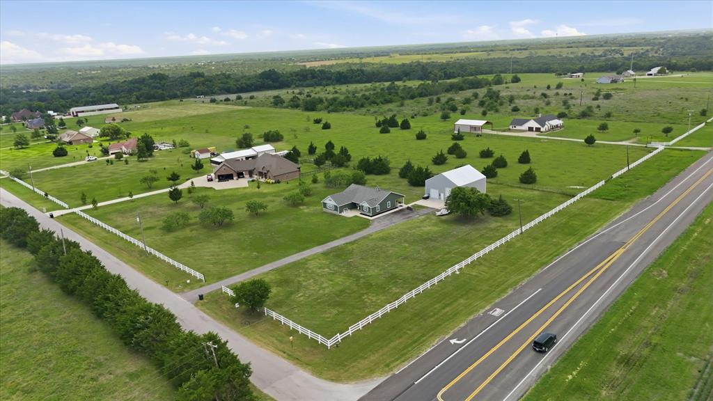 110 Highview Road Ennis, TX 75119 - Photo 39 of 40 Expansive rural property featuring a single-story residence, a large detached workshop, a white picket fence, and a paved highway frontage