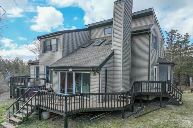 a view of a house with a wooden deck and furniture