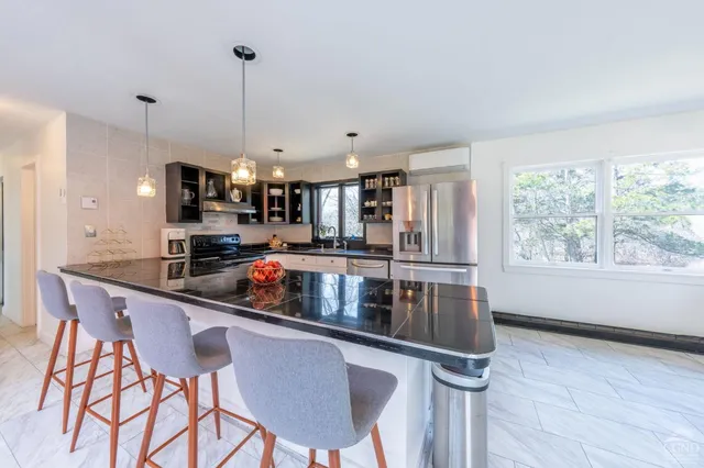 a kitchen with stainless steel appliances granite countertop a sink a stove a refrigerator cabinets and dining table