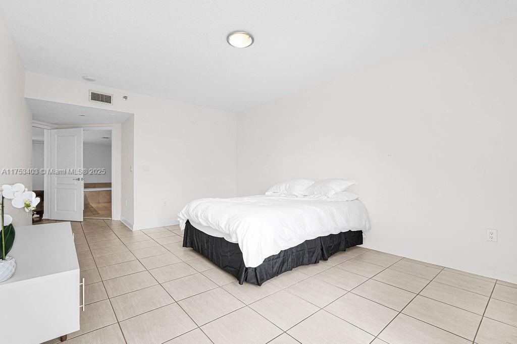 8925 Collins Avenue, Unit 2E Surfside, FL 33154 - Photo 20 of 46 a spacious bedroom with a bed and glass door