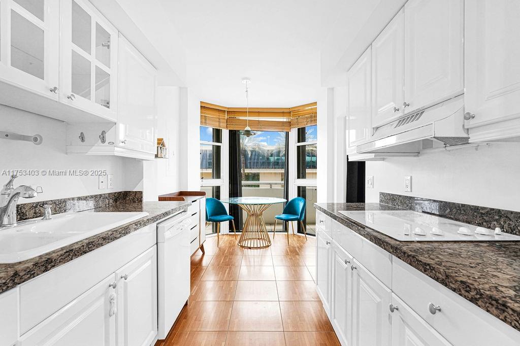 8925 Collins Avenue, Unit 2E Surfside, FL 33154 - Photo 28 of 46 a large white kitchen with stainless steel appliances granite countertop a sink stove and cabinets