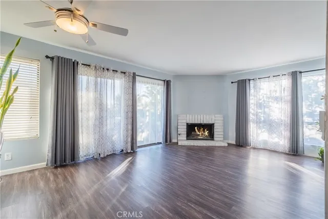 an empty room with windows a fireplace and wooden floor
