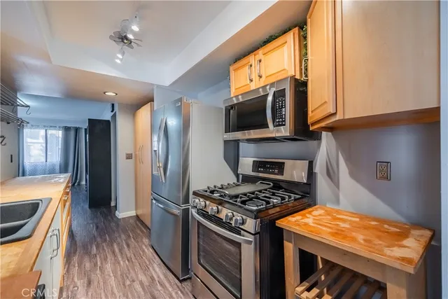 a kitchen with stainless steel appliances granite countertop a stove top oven a sink dishwasher and a refrigerator with wooden floor