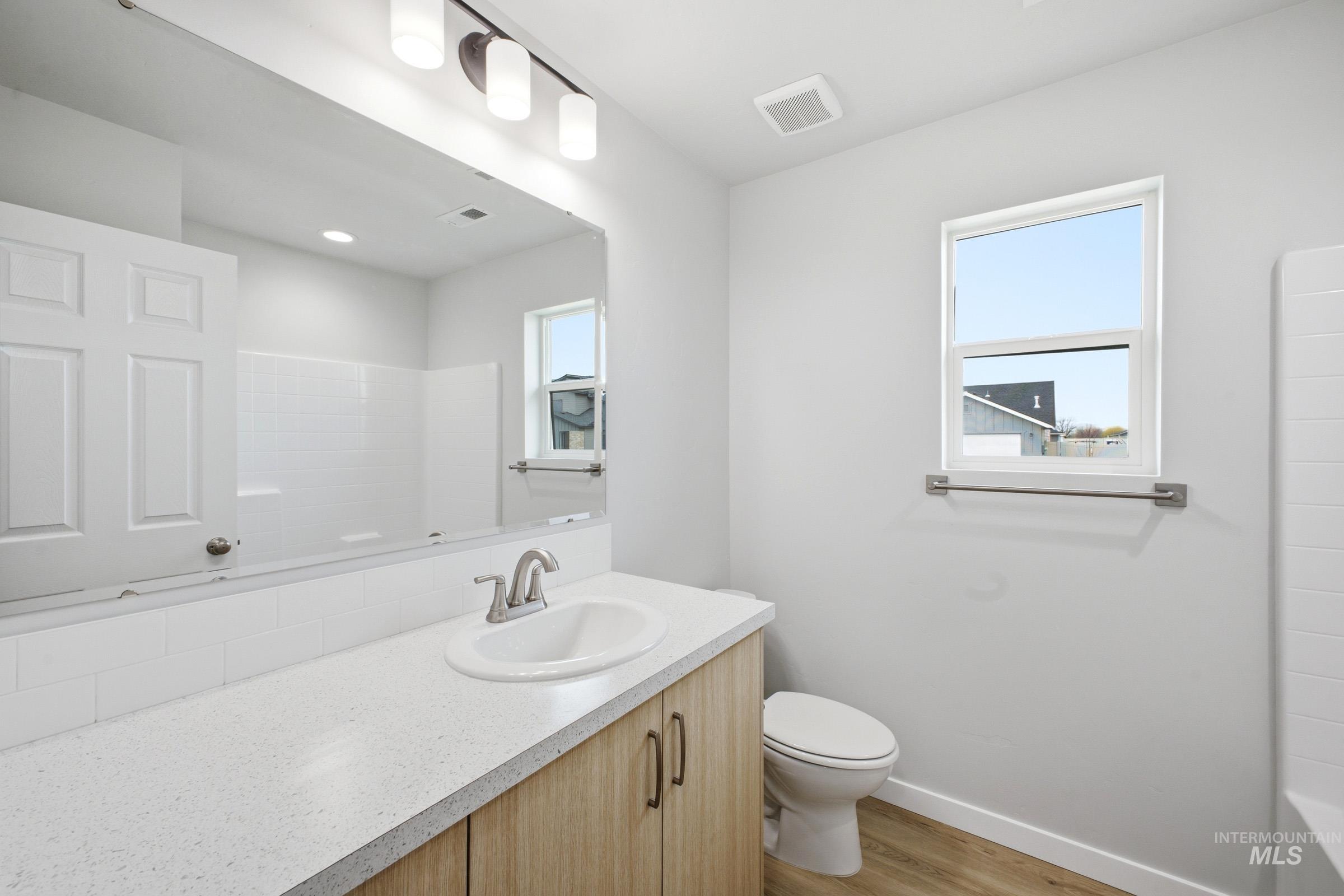 1598 Sunday River Street Middleton, ID 83644 - Photo 12 of 17 Bathroom featuring a light wood-finish vanity with a white countertop and integrated sink, a rectangular mirror, and a window providing natural illumination