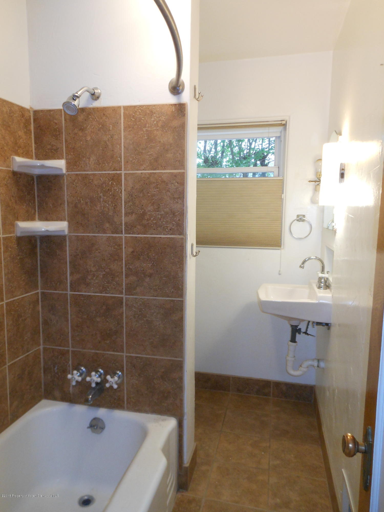 300 East 7th Street Rifle, CO 81650 - Photo 14 of 24 a bathroom with a bathtub a sink a window and vanity