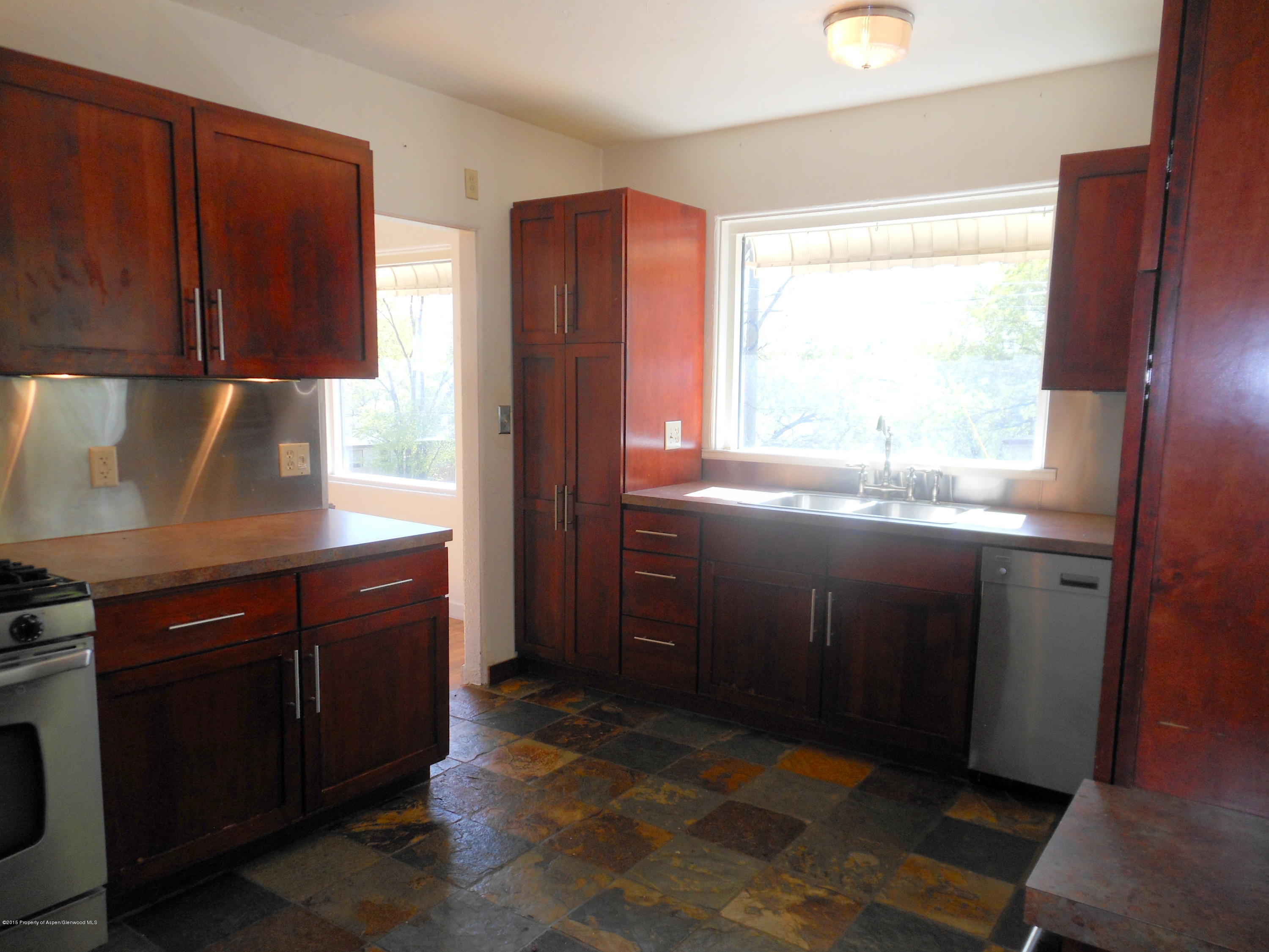 300 East 7th Street Rifle, CO 81650 - Photo 5 of 24 a kitchen with stainless steel appliances granite countertop a refrigerator a sink dishwasher and wooden cabinets