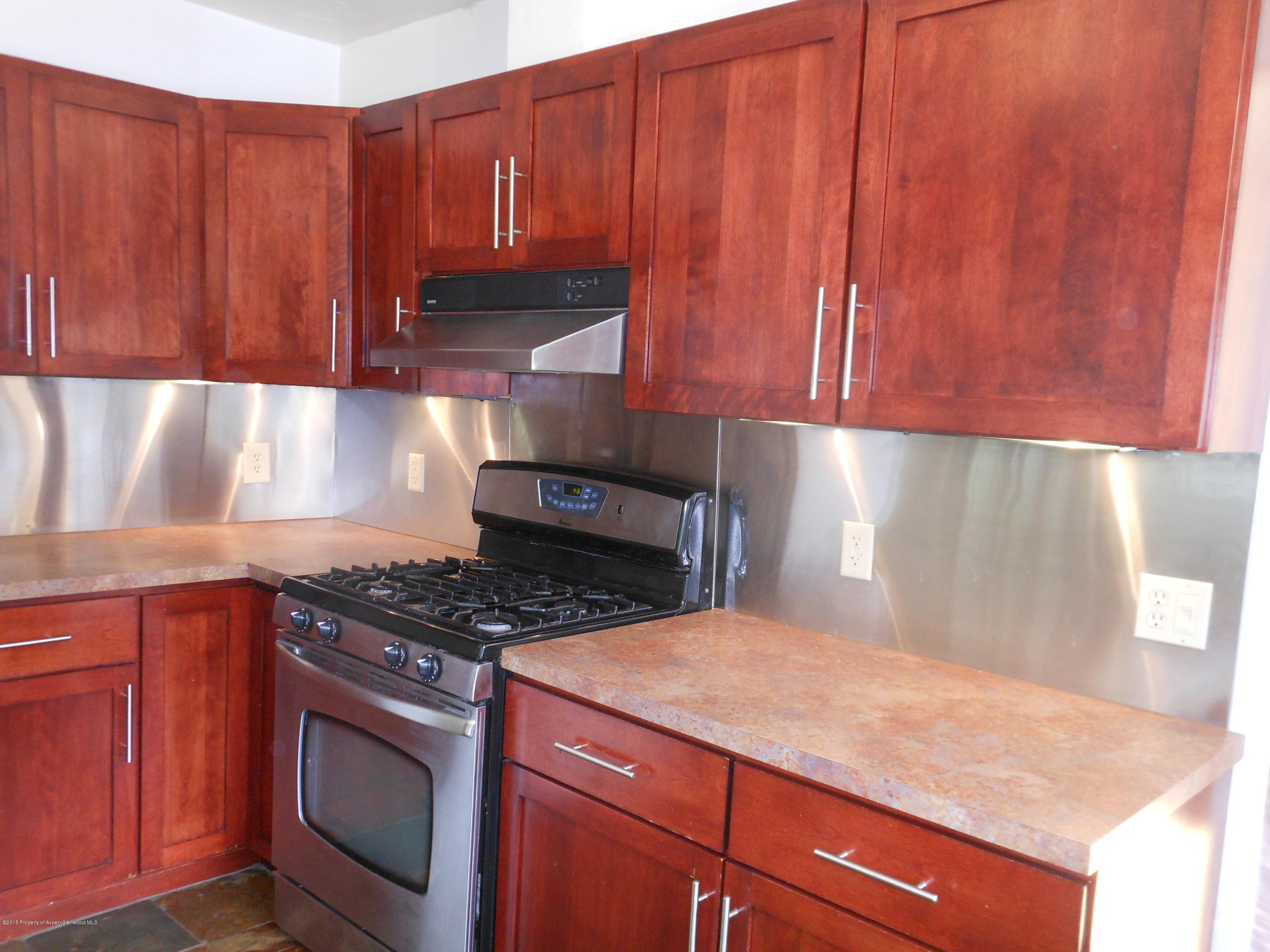 300 East 7th Street Rifle, CO 81650 - Photo 7 of 24 a kitchen with wooden cabinets and a stove top oven