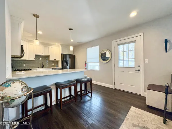 a open kitchen with stainless steel appliances granite countertop a living room dining room and wooden floor