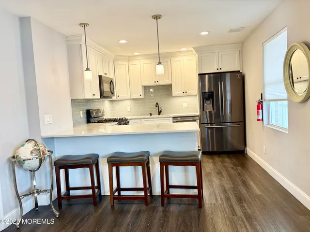 a kitchen with stainless steel appliances granite countertop a refrigerator a stove a sink dishwasher and a dining table with wooden floor