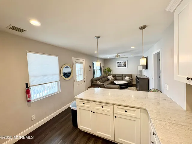 a kitchen with stainless steel appliances granite countertop a sink dishwasher a stove and white cabinets with wooden floor