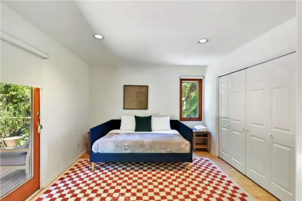 a bedroom with a bed and a potted plant on the dresser