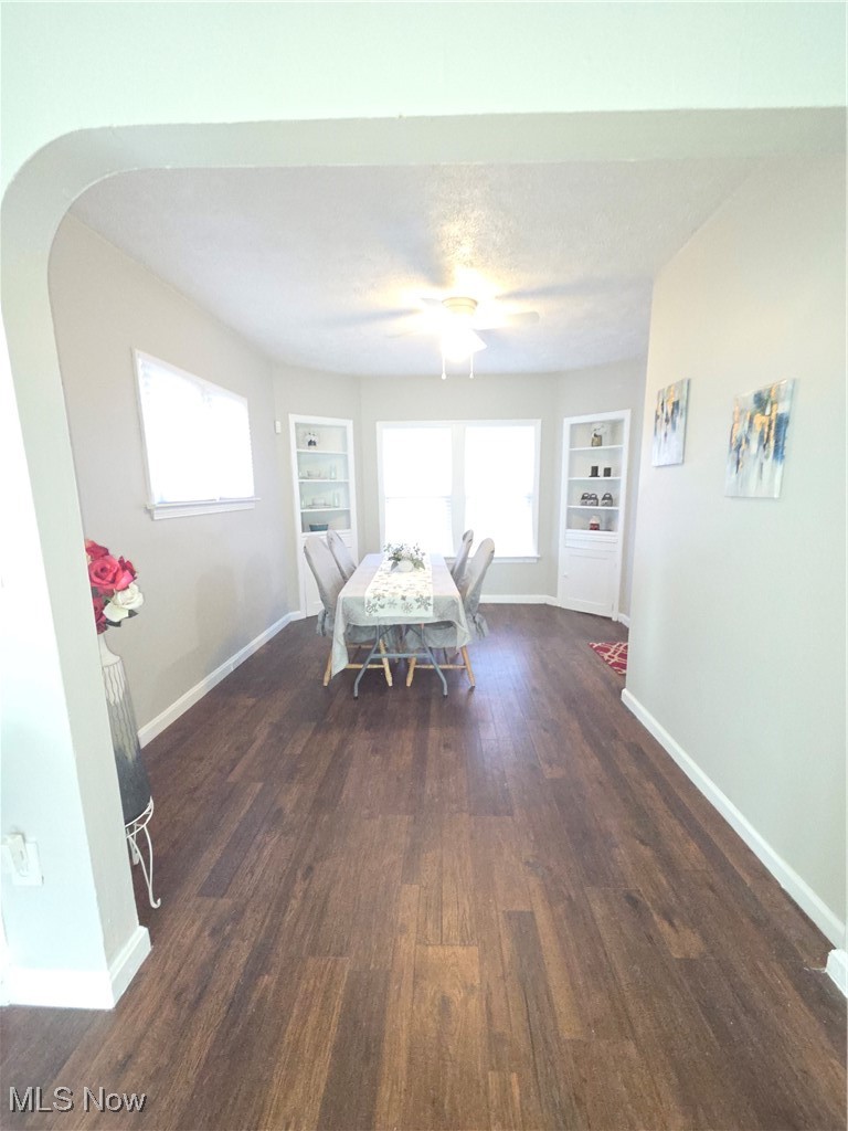 3797 Delmore Road Cleveland, OH 44121 - Photo 13 of 39 Dining room featuring dark wood-style flooring, built in shelves, arched walkways, and a textured ceiling