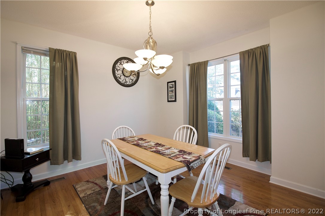 215 Kelly Road Pinehurst, NC 28374 - Photo 4 of 27 a dining room with wooden floor a chandelier a wooden table and chairs