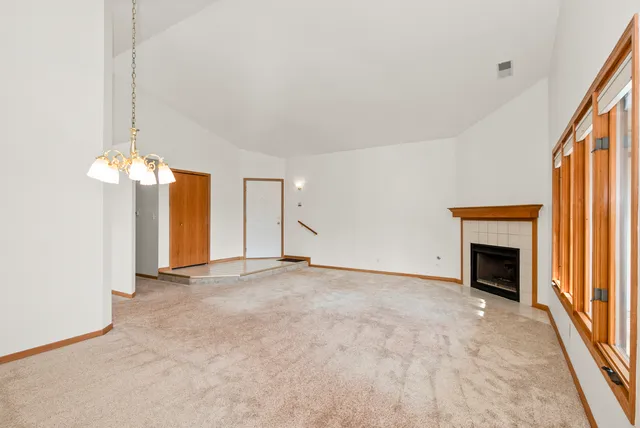 an empty room with a fireplace and chandelier