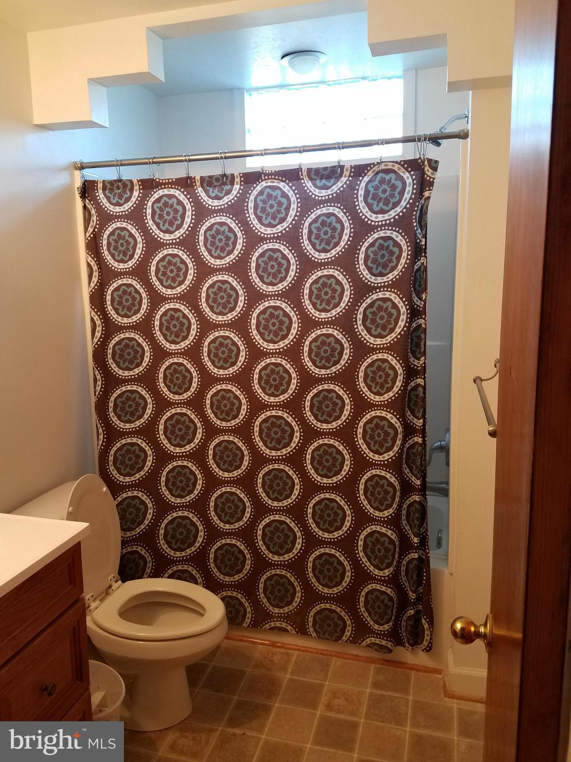 3203 River Drive Road Baltimore, MD 21219 - Photo 7 of 18 a bathroom with a toilet and a shower curtain