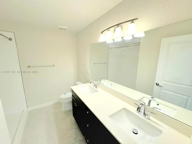 a bathroom with a double vanity sink mirror and shower