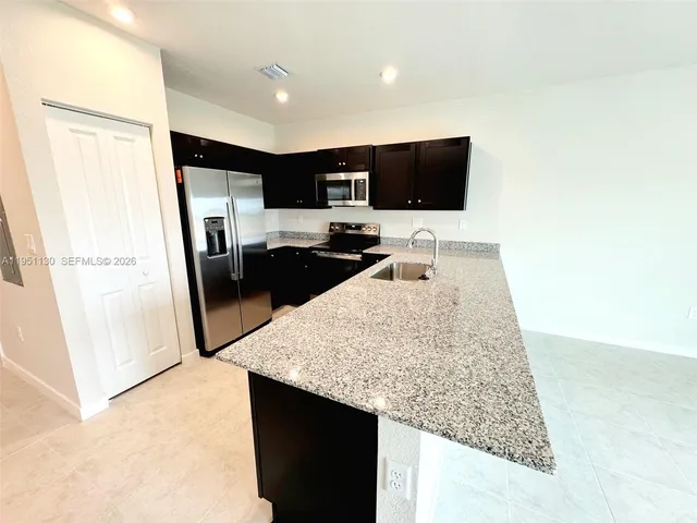 a kitchen with stainless steel appliances granite countertop a sink stove and refrigerator
