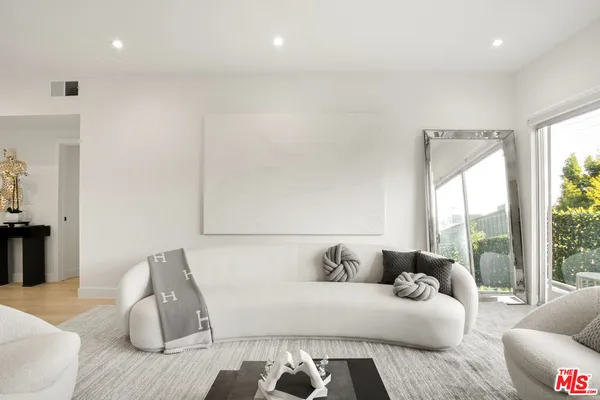 a living room with furniture kitchen view and a potted plant