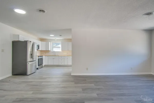 a view of a kitchen with refrigerator and wooden floor