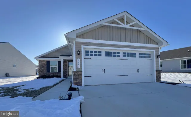 a front view of a house with a yard covered in snow