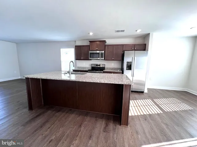 a kitchen with stainless steel appliances granite countertop a sink a stove top oven a counter space and cabinets