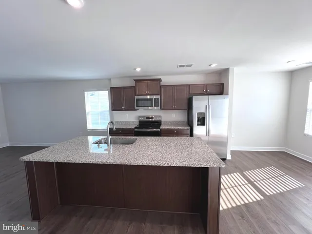 a kitchen with stainless steel appliances granite countertop a sink dishwasher a stove a refrigerator and cabinets with wooden floor