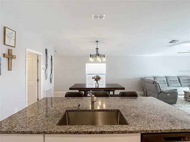 a kitchen with granite countertop a sink a stove and a wooden floor