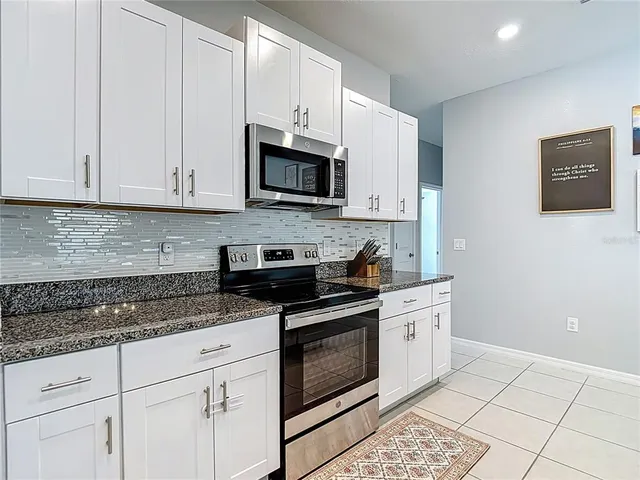 a kitchen with granite countertop white cabinets and stainless steel appliances