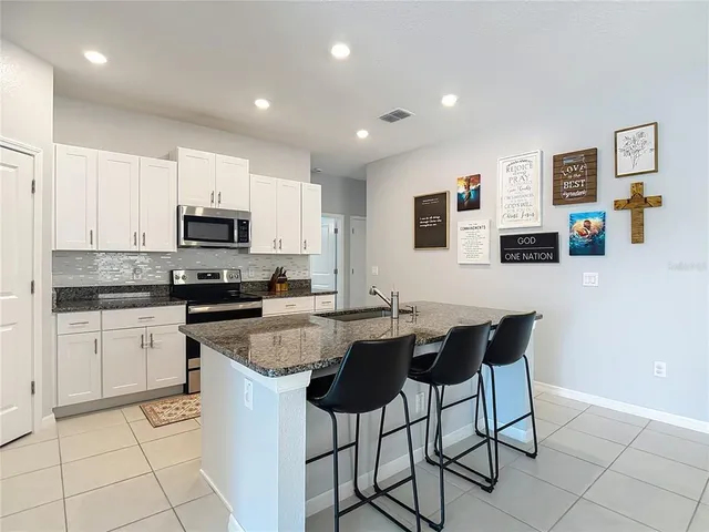 a kitchen with stainless steel appliances granite countertop a stove a sink a microwave a dining table and chairs