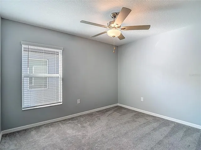 an empty room with a window and a fan