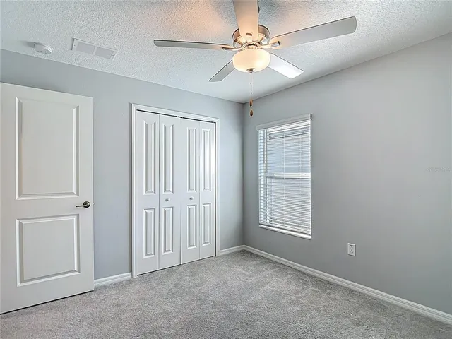 an empty room with windows and fan