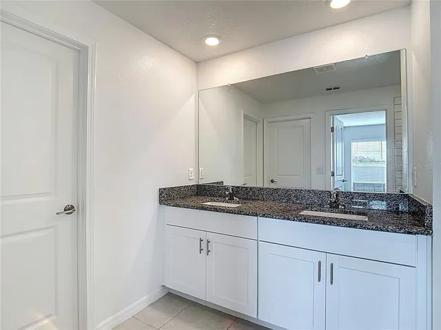 a bathroom with a granite countertop sink and a mirror