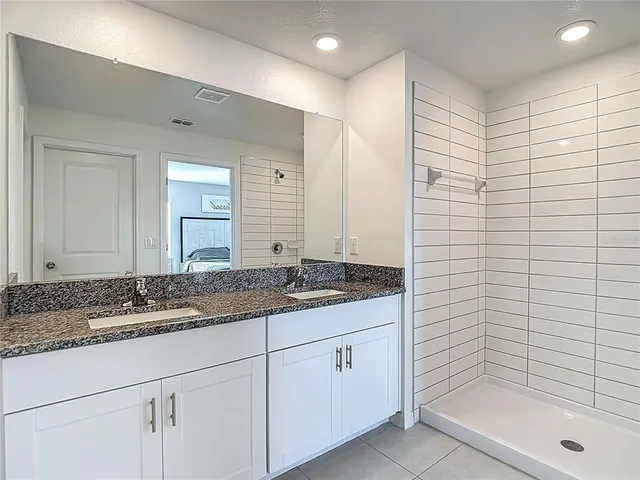 a bathroom with a granite countertop sink a shower and a mirror