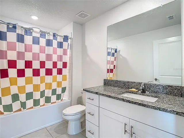 a bathroom with a granite countertop toilet a sink and a mirror