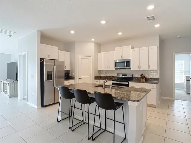 a kitchen with stainless steel appliances granite countertop a refrigerator and a stove top oven