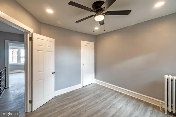 an empty room with wooden floor fan and windows