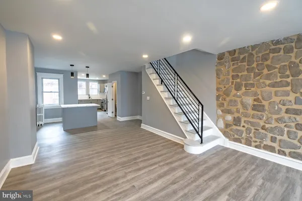 an empty room with wooden floor windows and stairs
